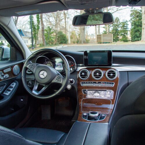 Front console and steering wheel of a Mercedes C-Class photographed from the rear seat.