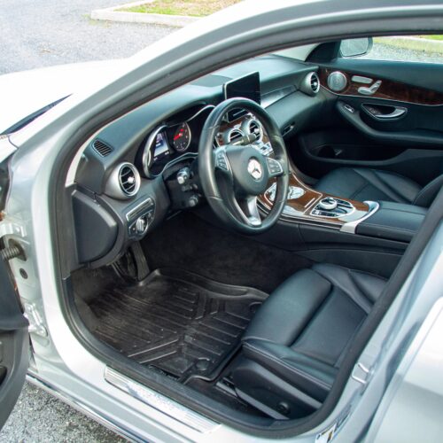 Mercedes C-Class parked in a lot photographed from the driver side showing the interior and the front seat.