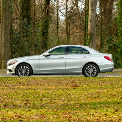 Mercedes C-Class parked in a lot photographed from the driver side.