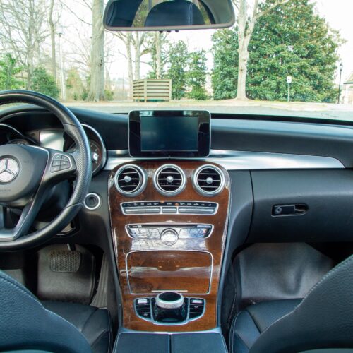 Front console and steering wheel of a Mercedes C-Class photographed from the rear seat.