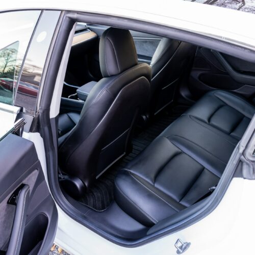 Tesla Model 3 photographed from the driver side showing the interior and the rear seat.