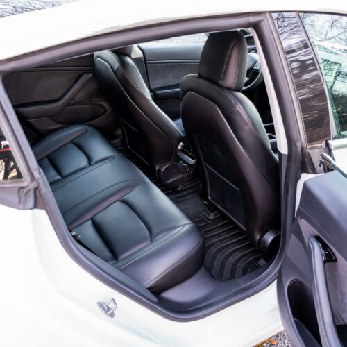 Tesla Model 3 photographed from the passenger side showing the interior and the rear seat.