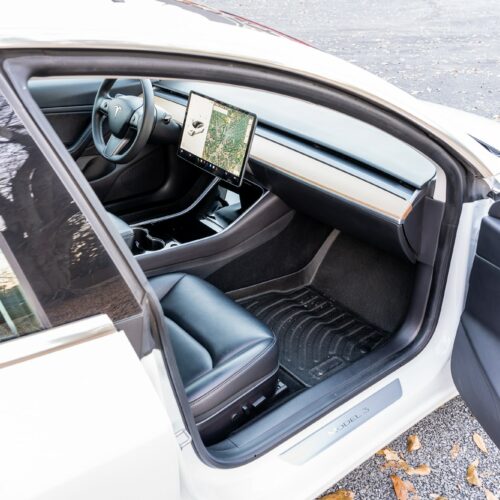 Tesla Model 3 photographed from the passenger side showing the interior and the front seat.