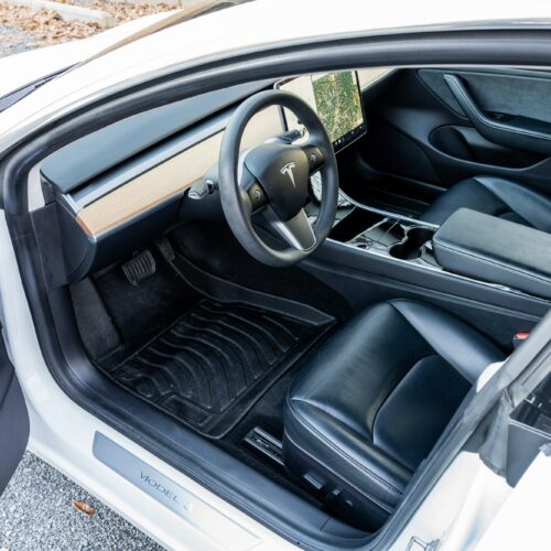 Tesla Model 3 photographed from the driver side showing the interior and the front seat.